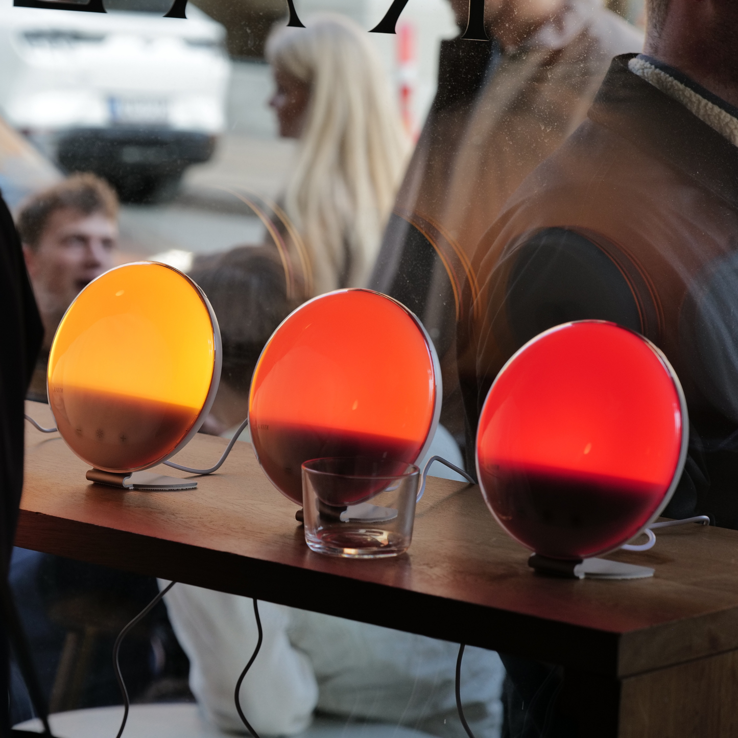 Multiple Kaydi One wake up lights placed on a table, each emitting different sunrise inspired light tones.